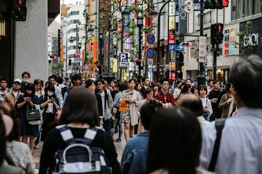 A busy urban street scene with people reading newspapers and using smartphones.