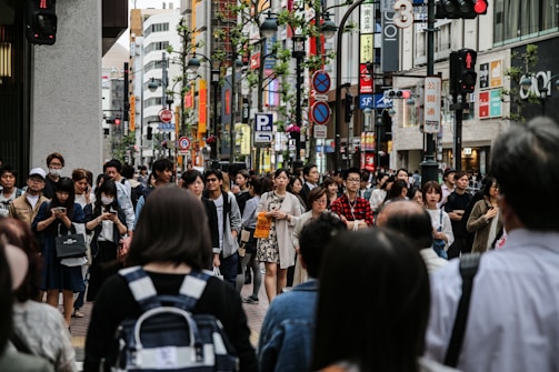 A city street bustling with people using various urban mobility apps on their smartphones.