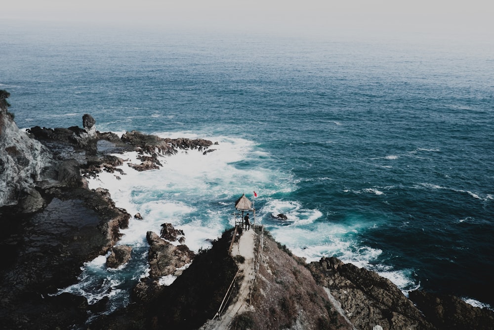 personne debout sur la falaise face à la mer verte