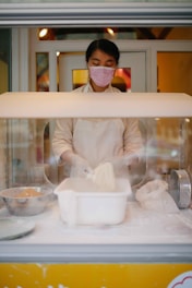 Image showing a baker wearing gloves and mask preparing dough in a spotless bakery kitchen.