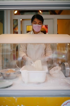 Image showing a baker wearing gloves and mask preparing dough in a spotless bakery kitchen.