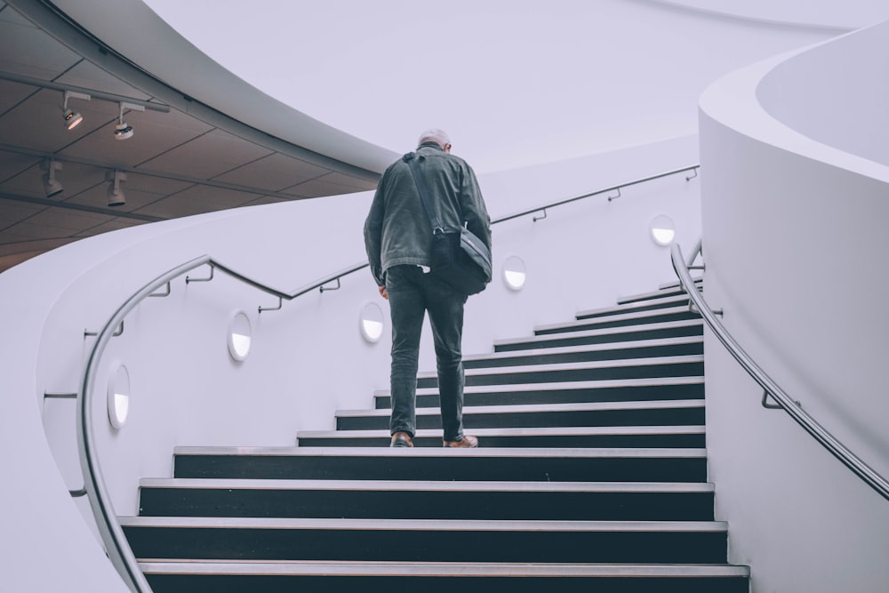 man wearing black jacket standing on black concrete stairs