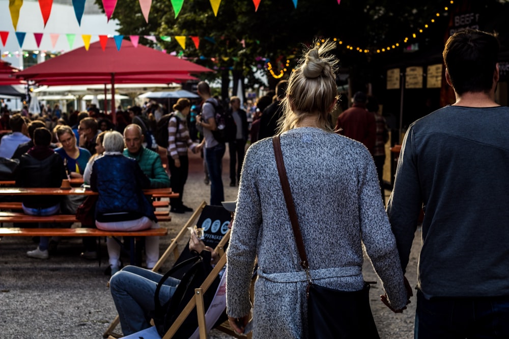 man and woman walking while holding hands during daytime