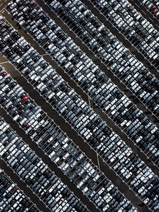 Aerial view of cars entering a busy parking lot with some empty spaces.