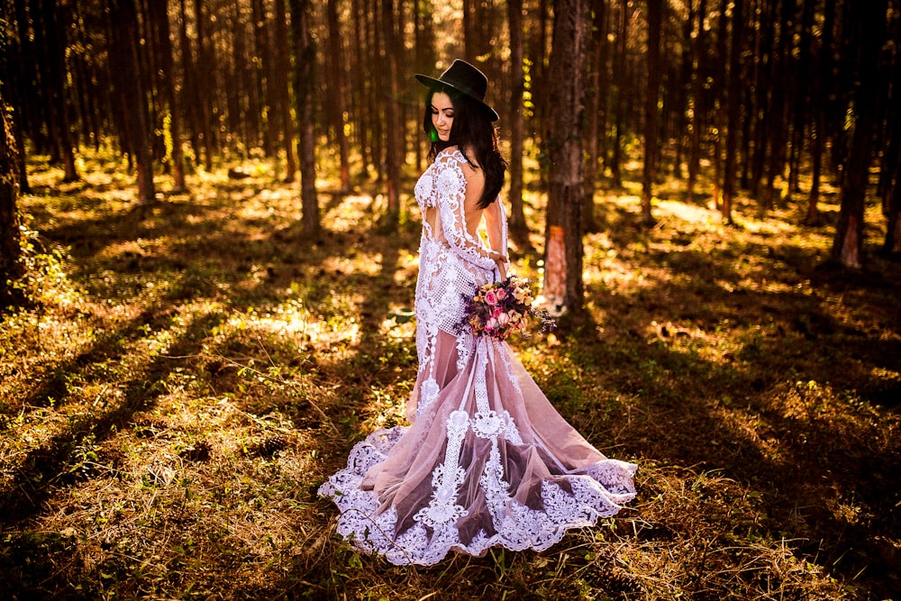 woman wearing white and grey lace dress standing in forest during daytime