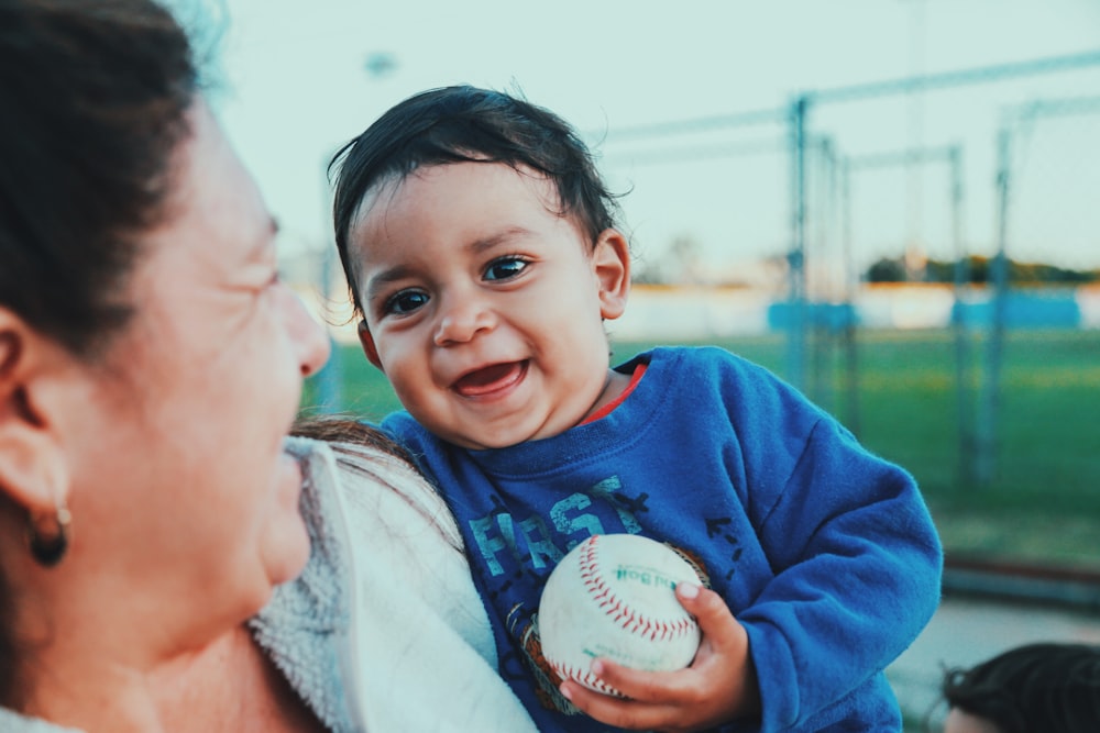 Foto de enfoque selectivo de bebé sosteniendo béisbol