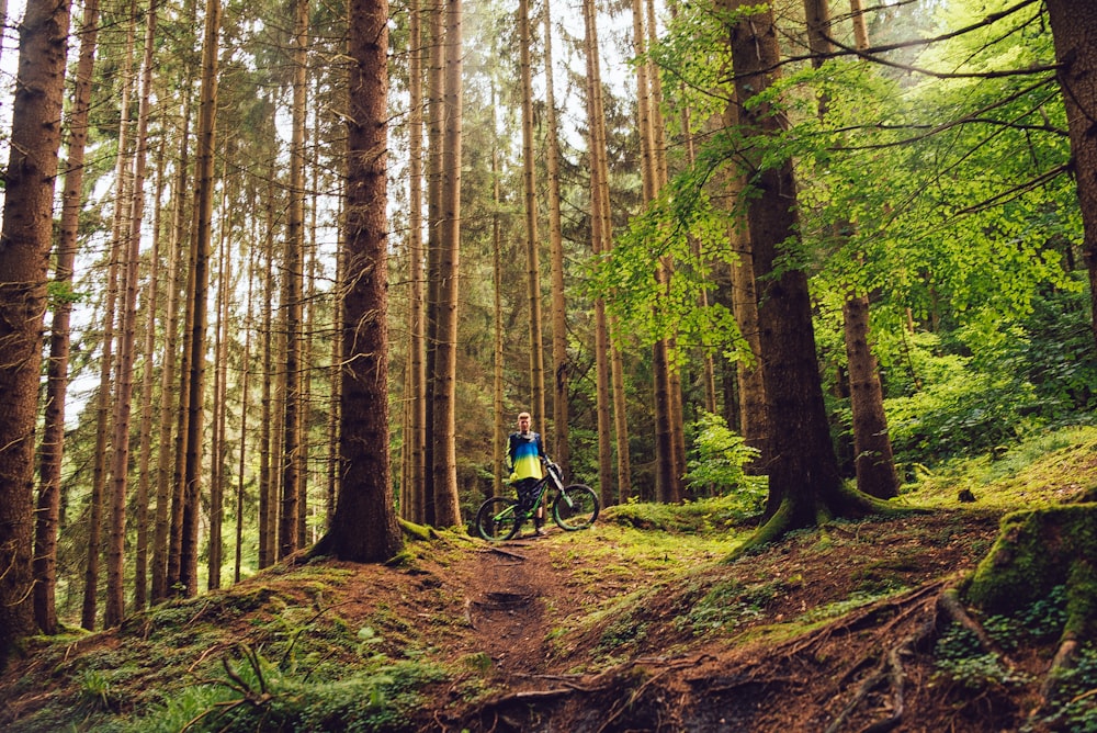 person holding a bike in a forest trees