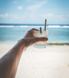 person holding drinking glass filled by straw