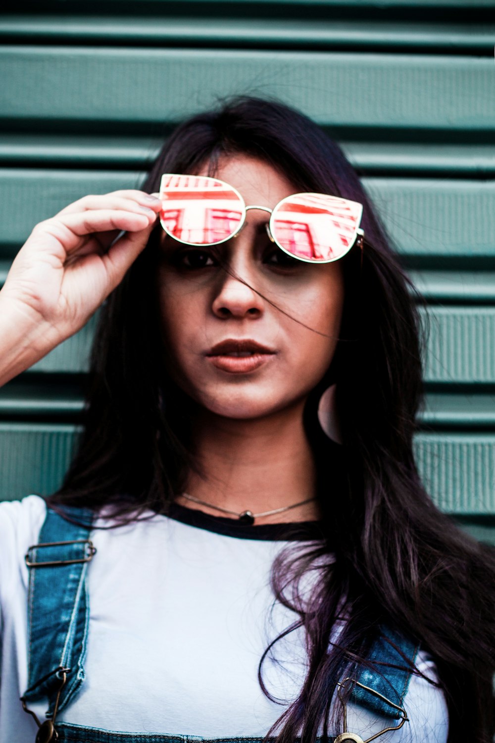 woman holding sunglasses near gray walpl