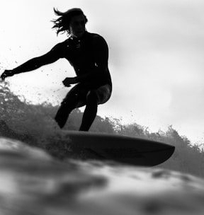 grayscale photo of man riding a surfboard