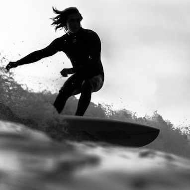 grayscale photo of man riding a surfboard
