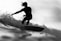 grayscale photo of man riding a surfboard