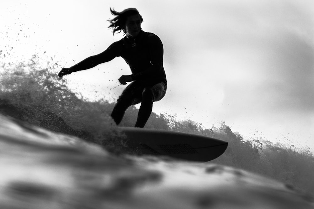 Foto en escala de grises de un hombre montando una tabla de surf