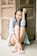 smiling woman sitting on floor back of wooden wall