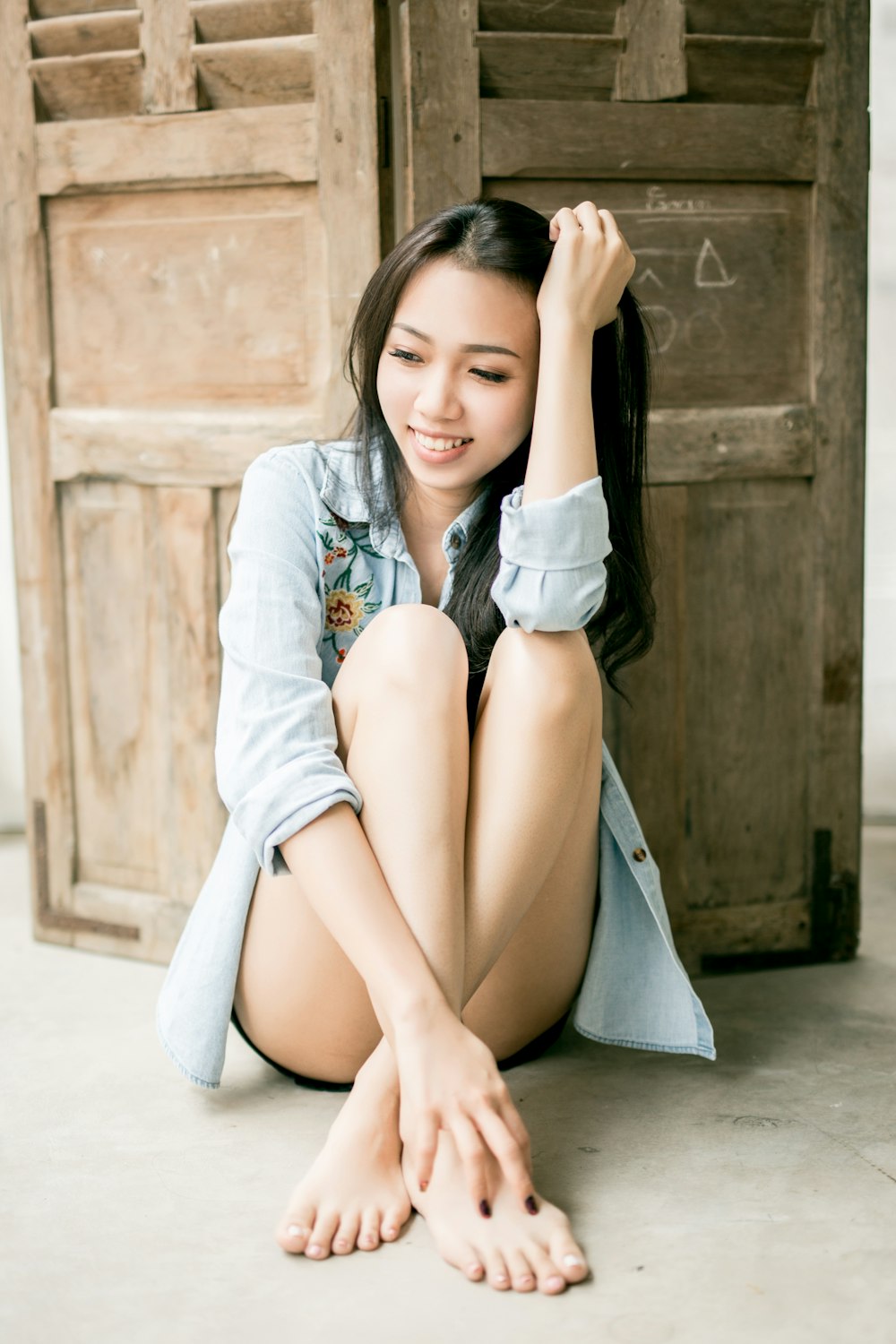 smiling woman sitting on floor back of wooden wall