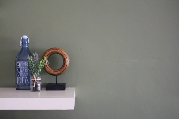 A minimalist kitchen shelf featuring an Oleivo pouch next to a bottle of natural wine and fresh herbs.