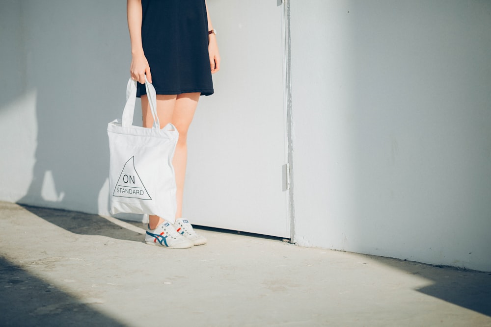 woman holding bag while standing near wall