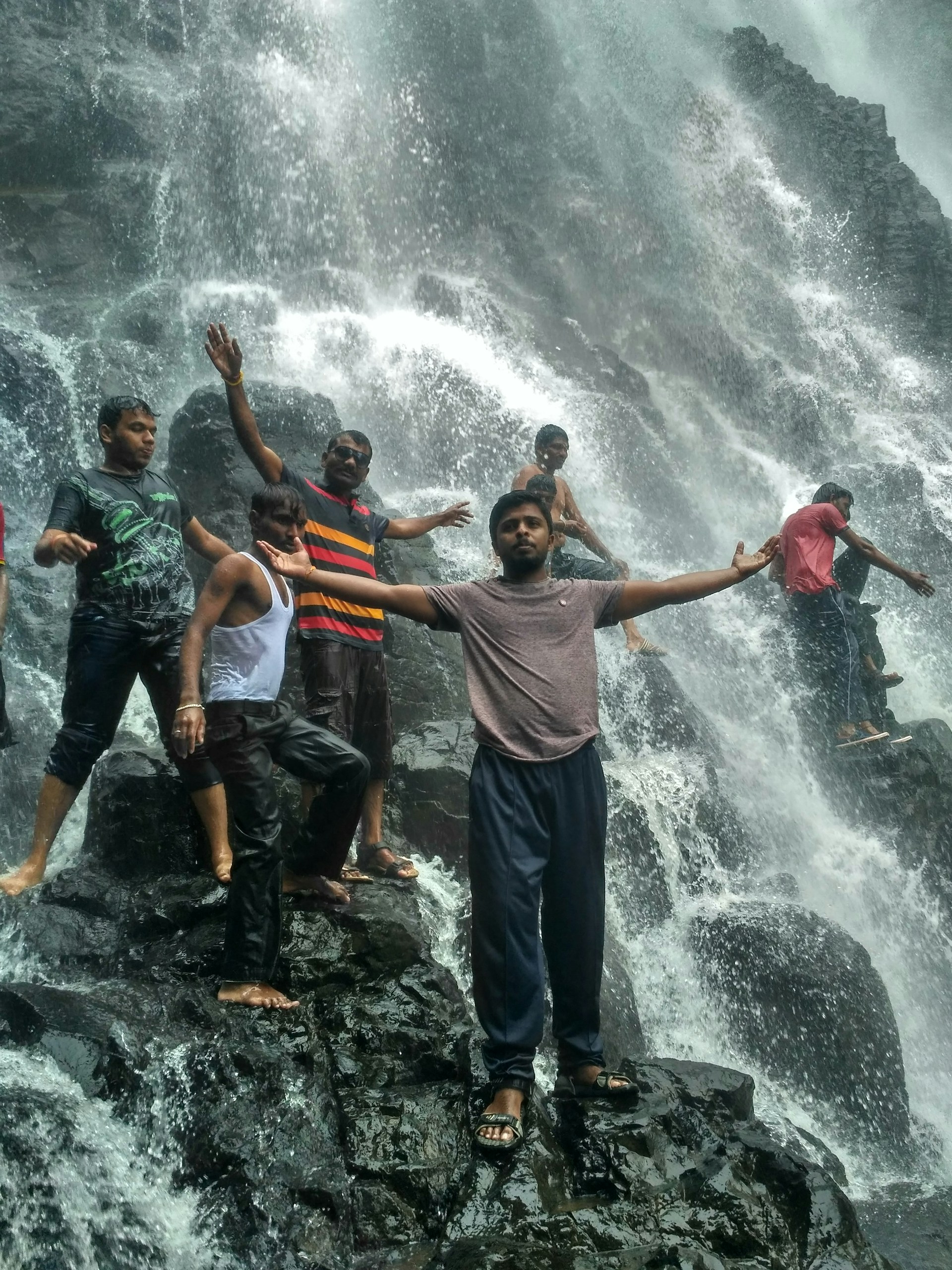 A joyful group of tourists laughing and posing on a rocky beach, with the vibrant cityscape of Cape Town in the background.