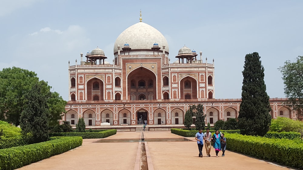 group of four people walking near mosque