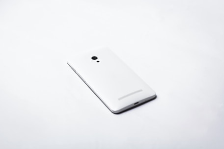 A sleek minimalist smartphone resting on a clean white surface with soft natural light.