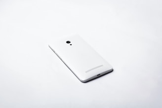 Minimalist sleek smartphone on a clean white surface with soft natural lighting
