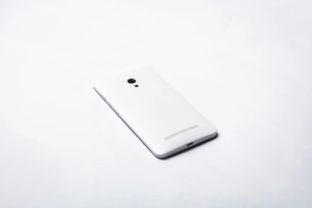 Close-up of a sleek, modern smartphone resting on a clean white surface.