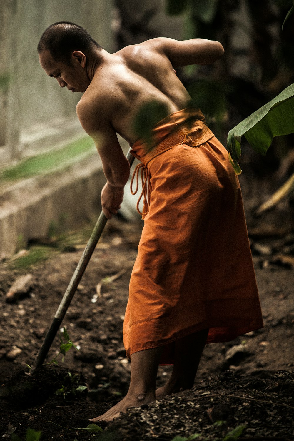 monk gardening near grey wall