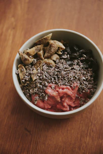 A bowl filled with vibrant superfood powders surrounded by fresh fruits and nuts.