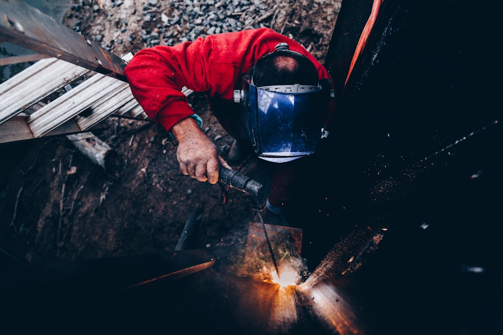 hombre sosteniendo la máquina de soldar y usando una máscara de soldadura