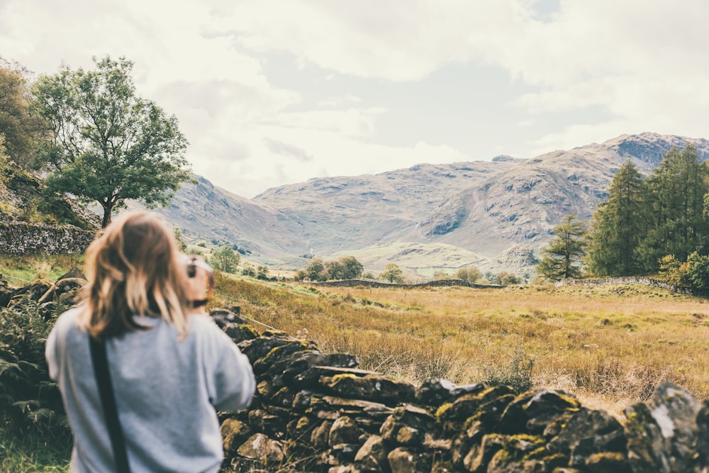 woman taking photo of brown mountain