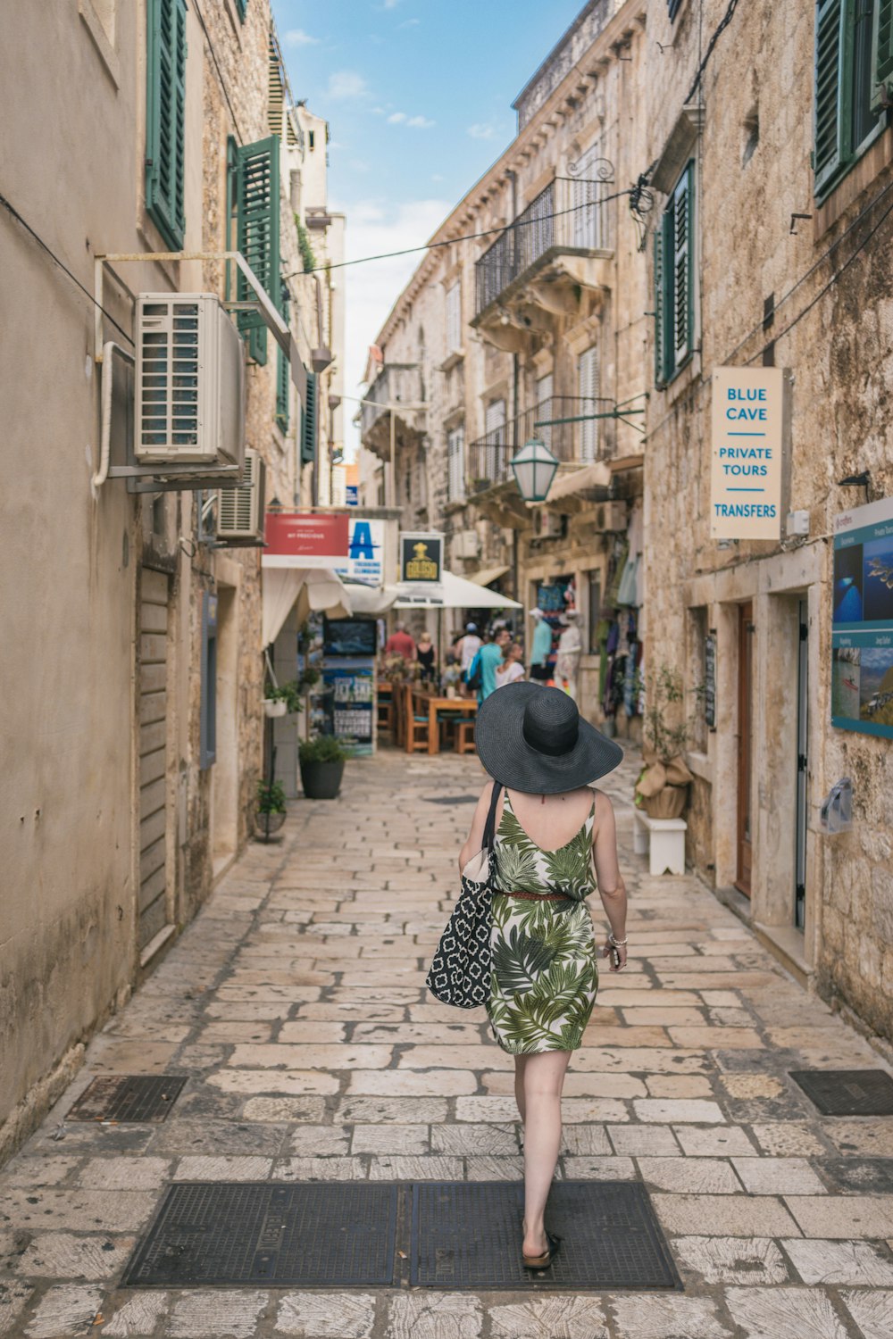 woman walking between brown concrete buildings during daytime