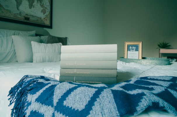 A bedroom nook with a neatly folded blanket and a small stack of books on a bedside table.