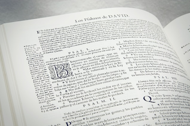 An open book displaying text in Spanish. The text includes headings, paragraphs, and some stylized letters. The content appears to be religious or historical in nature, with references to Psalms. The layout is dense with a small font size.