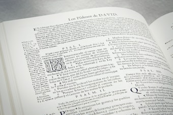An open book displaying text in Spanish. The text includes headings, paragraphs, and some stylized letters. The content appears to be religious or historical in nature, with references to Psalms. The layout is dense with a small font size.
