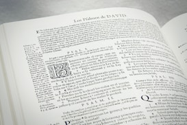 An open book displaying text in Spanish. The text includes headings, paragraphs, and some stylized letters. The content appears to be religious or historical in nature, with references to Psalms. The layout is dense with a small font size.