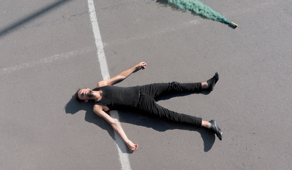 woman in black tank top and black pants lying on gray concrete floor