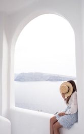 person holding hat sitting on edge