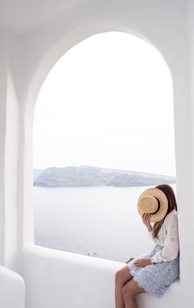 person holding hat sitting on edge