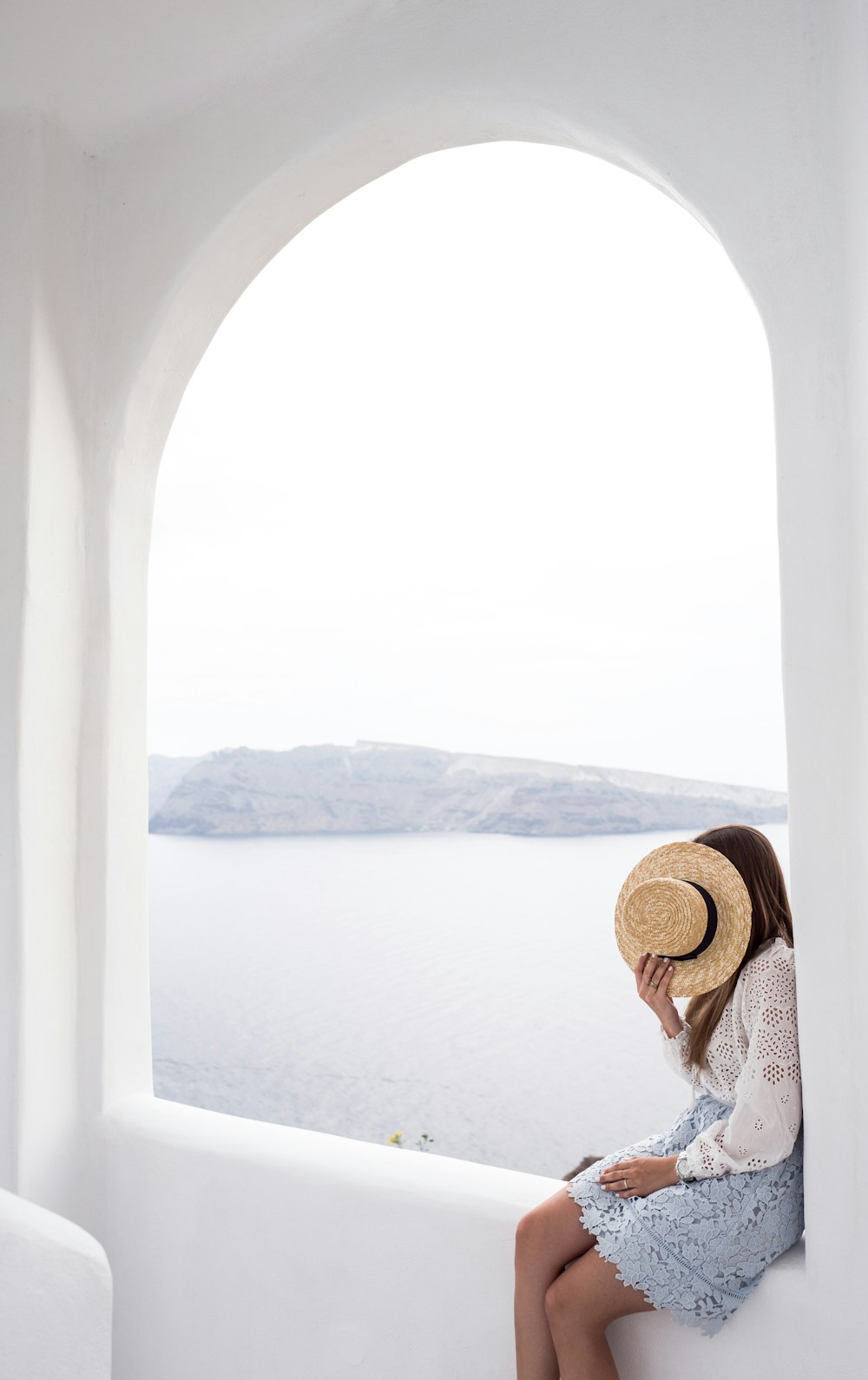 person holding hat sitting on edge