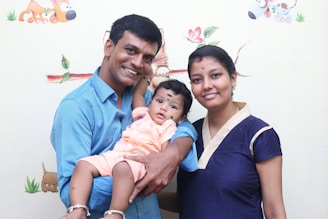 A smiling parent holding a baby surrounded by colorful baby products.
