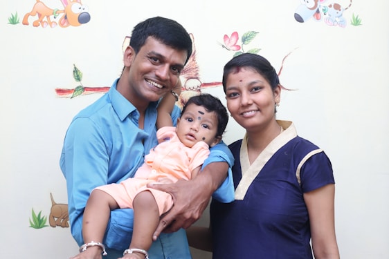 A smiling parent holding a baby surrounded by colorful baby products.
