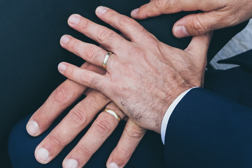 Mãos de dois homens usando alianças de casamento douradas