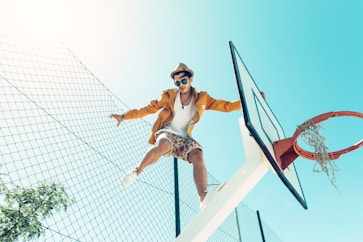man standing on basketball hoop system stand during daytime