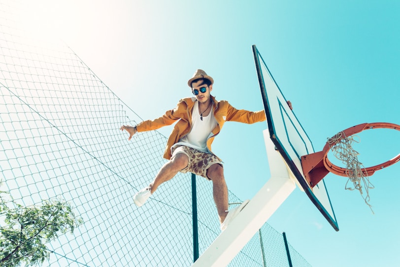 man standing on basketball hoop system stand during daytime