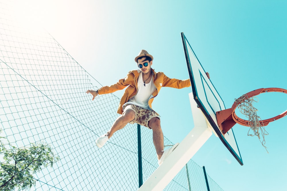 man standing on basketball hoop system stand during daytime