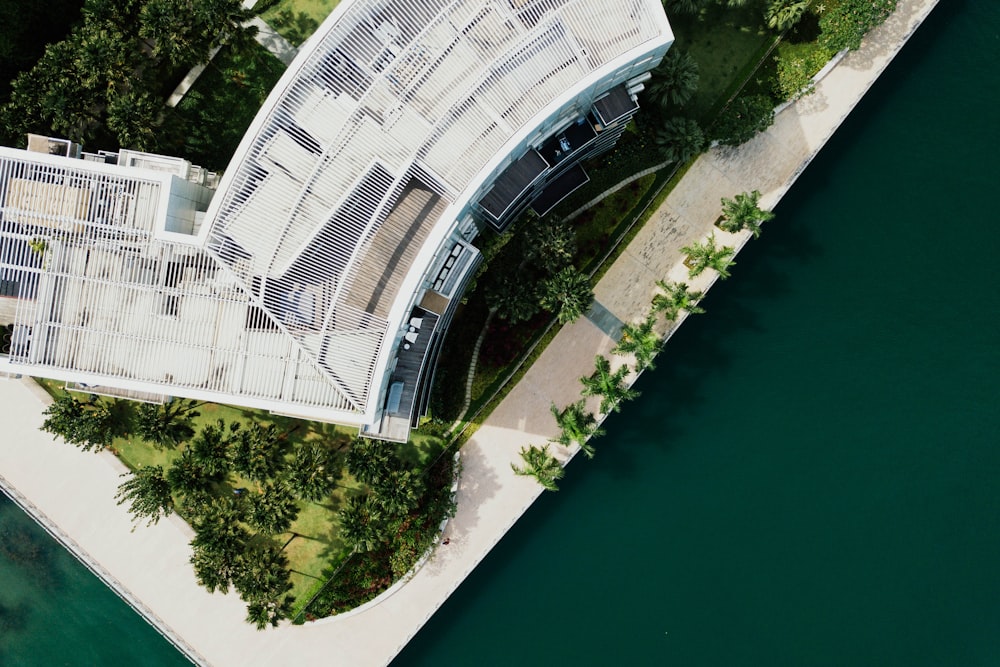 bird's eye view photography of a mid-rise building surrounded by trees near green body of water