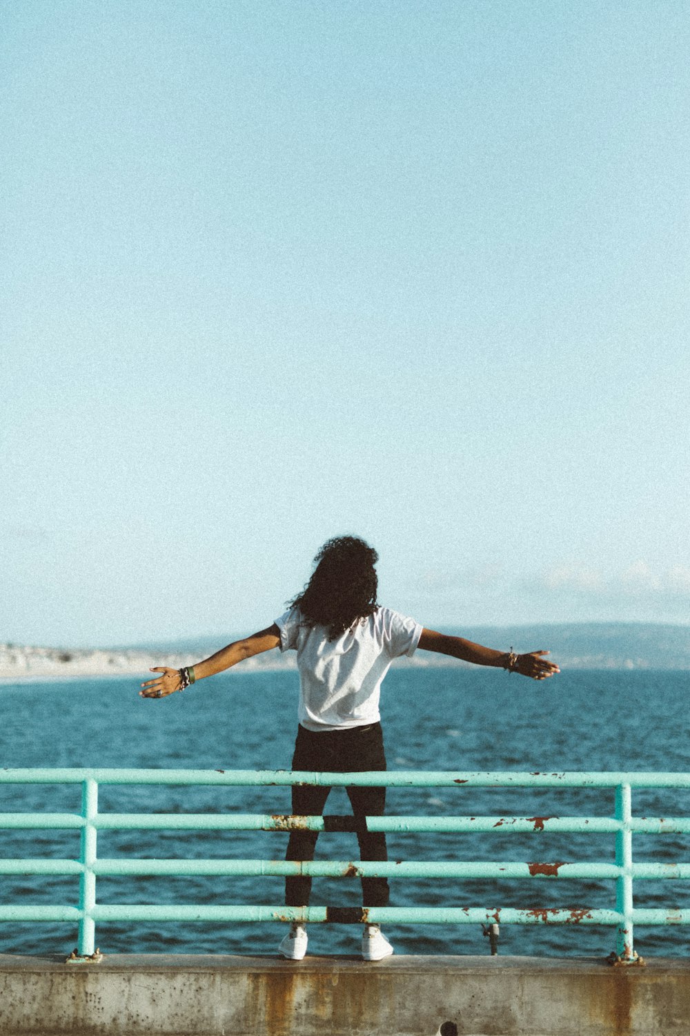 woman standing in front of sea under clear blue sky