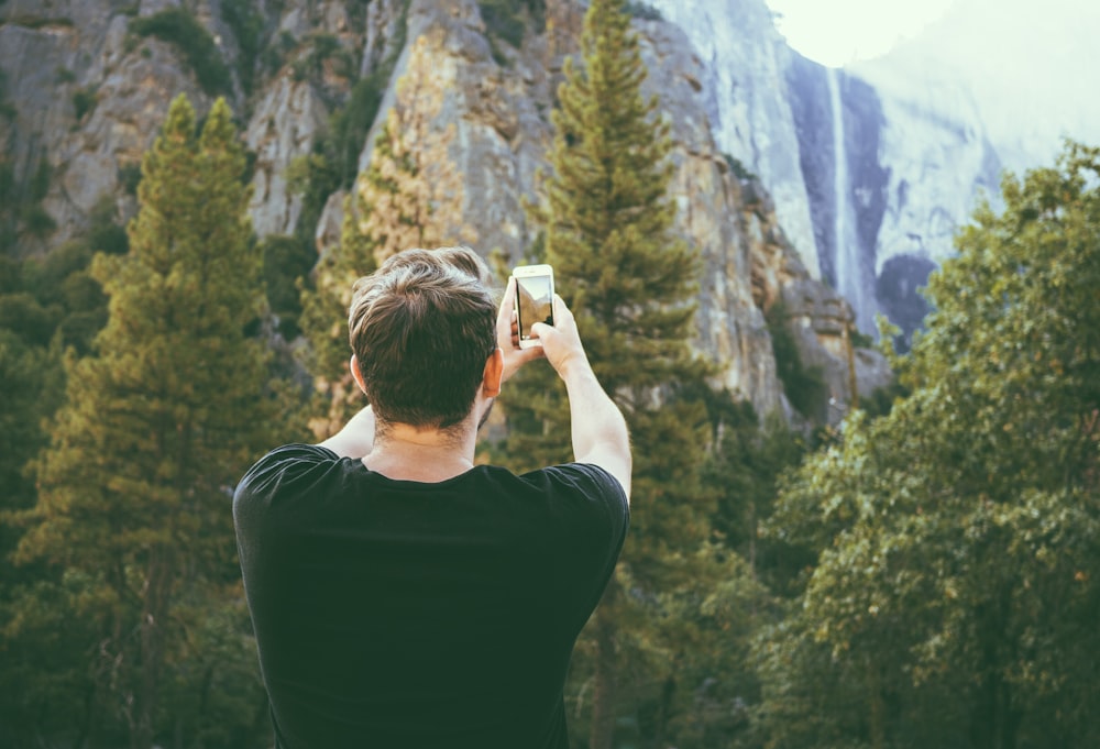 man taking photo of mountains