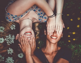 man and woman smiling while laying on lawn field