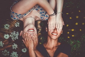man and woman smiling while laying on lawn field